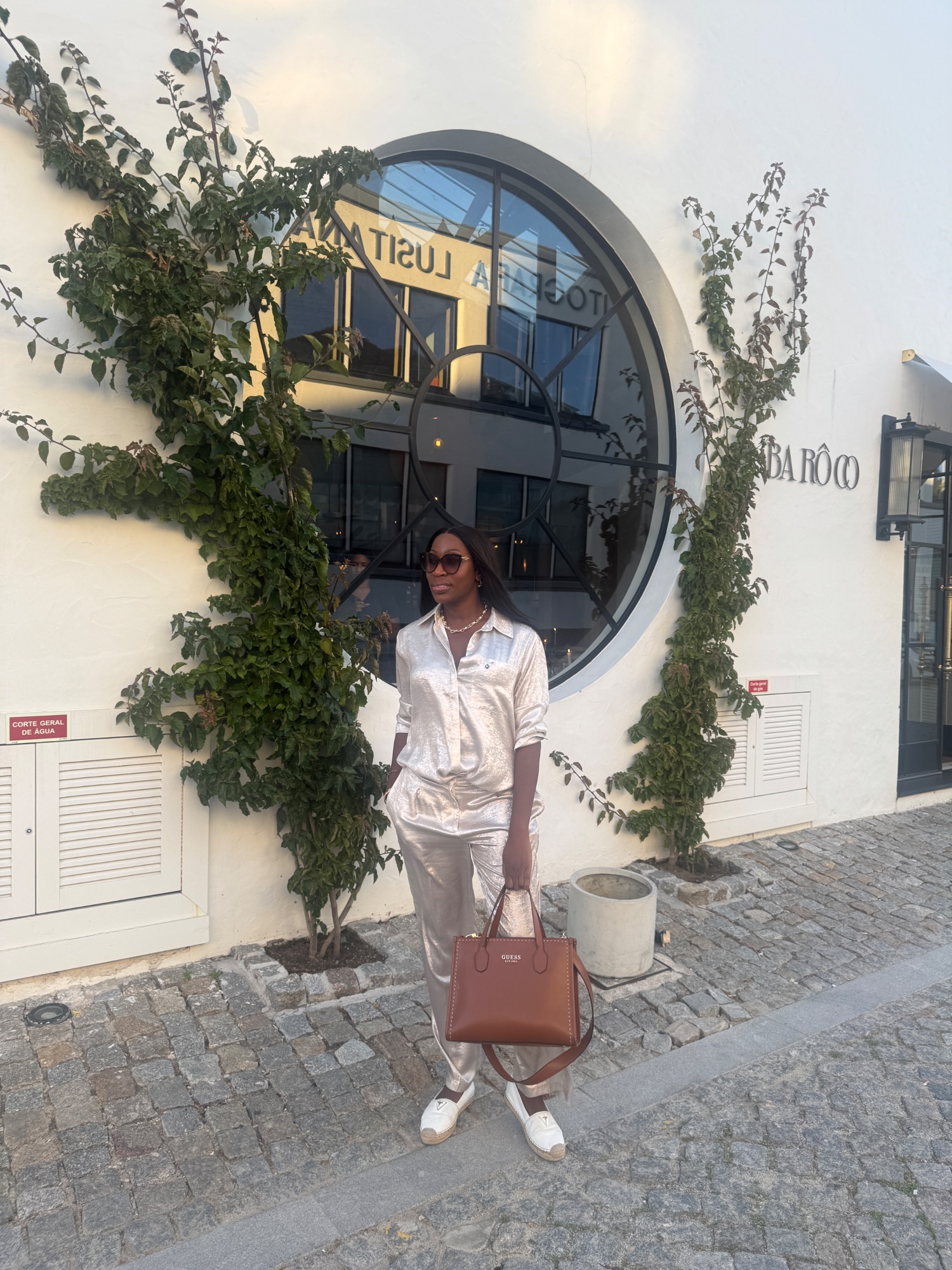 Vanessa in a champagne satin suit outside a restaurant in Portugal at golden hour