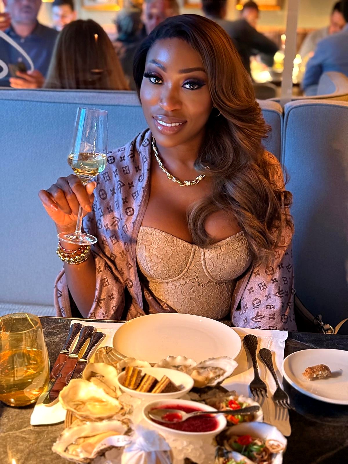 Vanessa in an evening outfit raising a glass at a fine-dining table