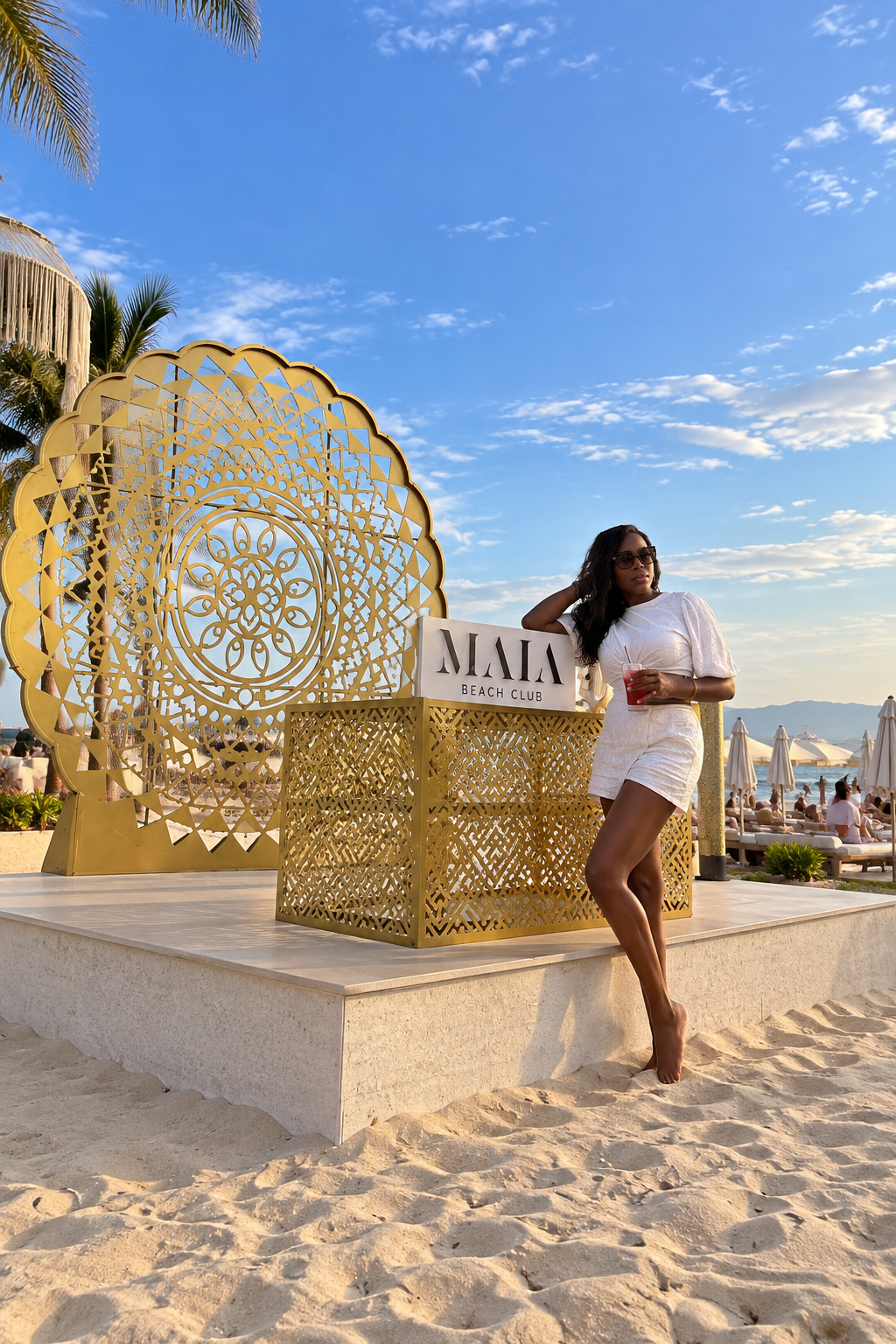 Vanessa on a Da Nang beach beside a gold filigree art installation under a blue sky